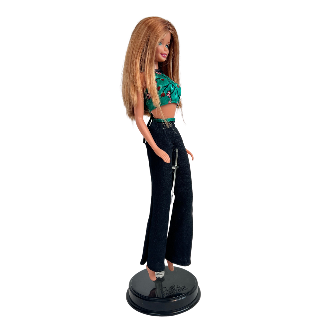 Barbie Style è una produzione del 1998. Questa bambola indossa un top verde con inserti rossi e dei jeans molto casual scuri. Ha i capelli castano chiaro e sono lunghi.