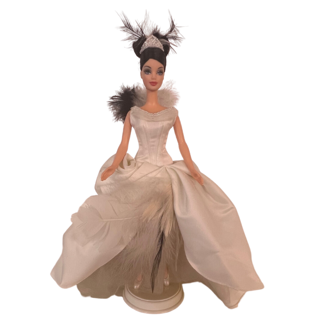 Barbie The Swan 2000 è una realizzazione Mattel del 2000 In questa versione possiamo vedere Barbie trasformarsi in un meraviglioso e leggiadro cigno nel suo abito da sera bianco con strascico e pence sulla coda, davanti più corto con dettagli di piume di cigno bianco e nero. Qualche difetto nel vestito.