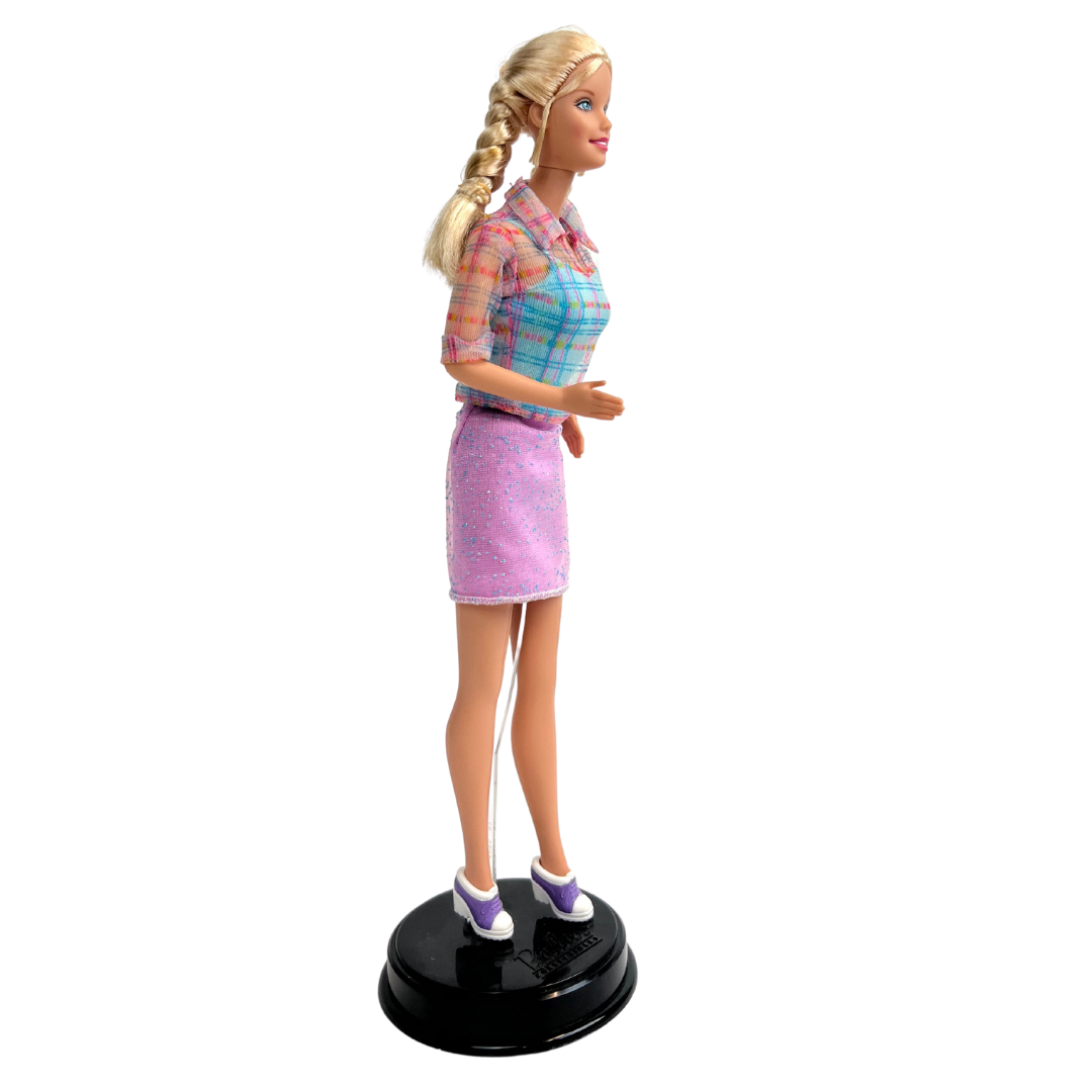 La bambola Barbie dai capelli biondi e occhi azzurri indossa una gonna viola scintillante, un top blu con strisce trasparenti sopra, un paio di scarpe viola e bianche. manca passeggino e bambola piccola