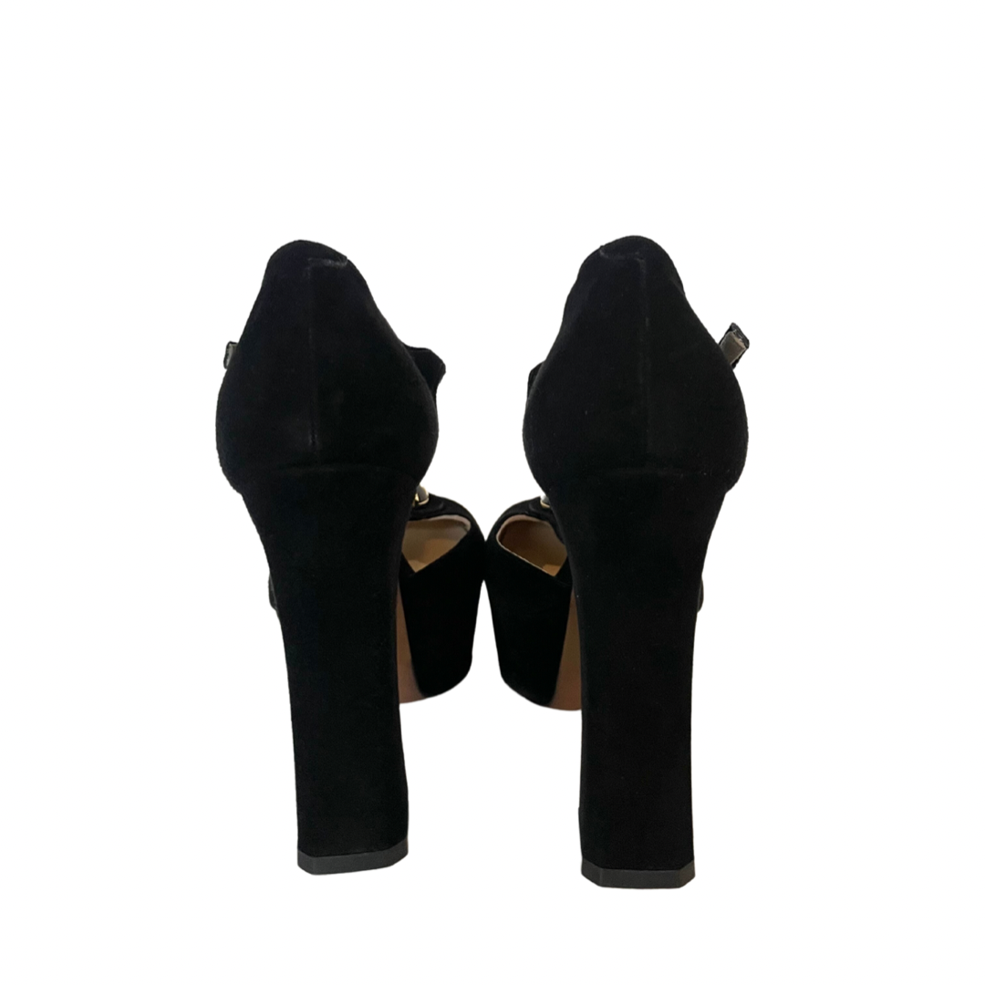 Scarpa decolletè scamosciata nera con pietra centrale, tacco alto e grosso con cinturino alla caviglia e plateaux. Altezza tacco : 11.5 cm Altezza plateaux 3.5 cm