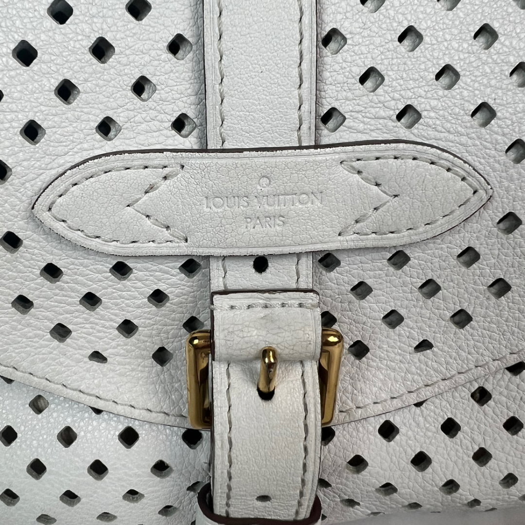Immergiti nel lusso con la nostra Borsa 'Saumur’ di Louis Vuitton, in pelle traforata bianca, realizzata per la collezione Croisette del 2012. Questa borsa, pari al nuovo, presenta una doppia patella e una pratica tracolla regolabile per rendere la tua borsa pratica e leggerissima questa borsa è l'accessorio ideale per una donna dinamica ma che ci tiene ad essere fashion in maniera discreta.