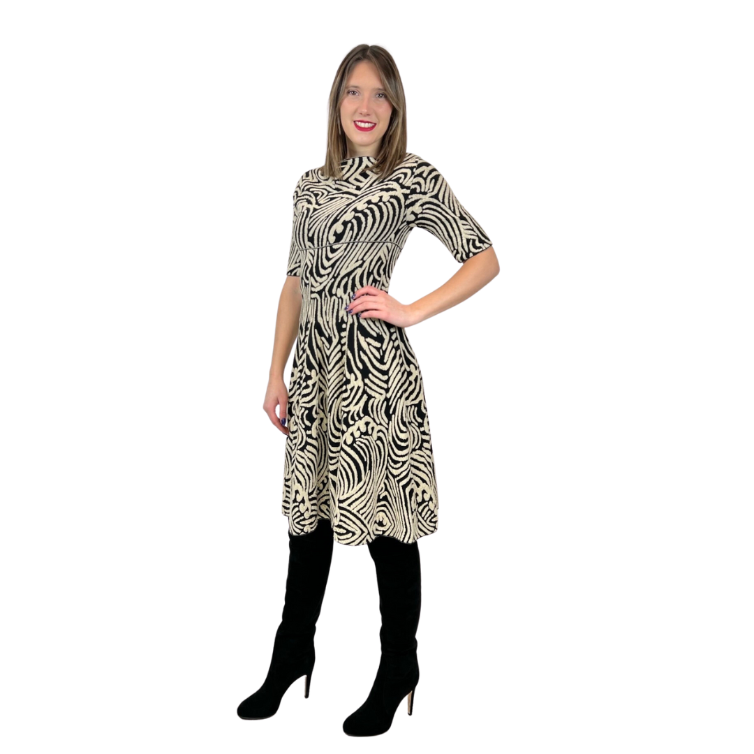 Abito in maglia di lana con fondo nero e con disegni irregolari sui toni del beige chiaro. Collo a barchetta e gonna a ruota, manica a 3/4. Tg. L