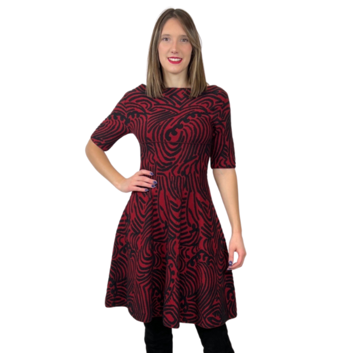 Abito in maglia di lana con fondo nero e con disegni irregolari sui toni del rosso. Collo a barchetta e gonna a ruota, manica a 3/4. Tg. L