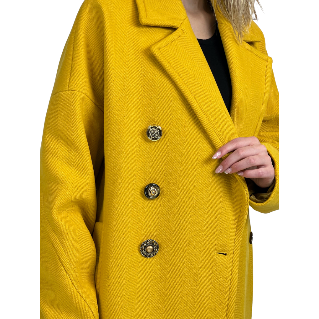 Cappotto lungo giallo ocra con tessuto fatto a costine, chiusura con bottoni gioiello diversi tra loro. Vestibilità Over.