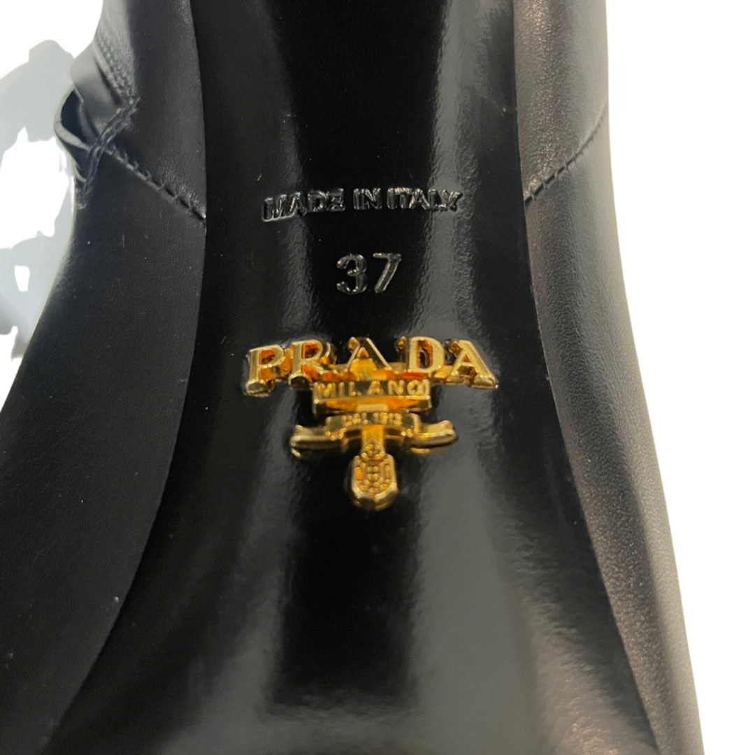 Scarpa stivaletto nero con gambale basso sopra alla caviglia in pelle liscia e leggermente a punta. Con logo oro sulla suola. Altezza del tacco: 11 cm con plateaux interno di 3 cm