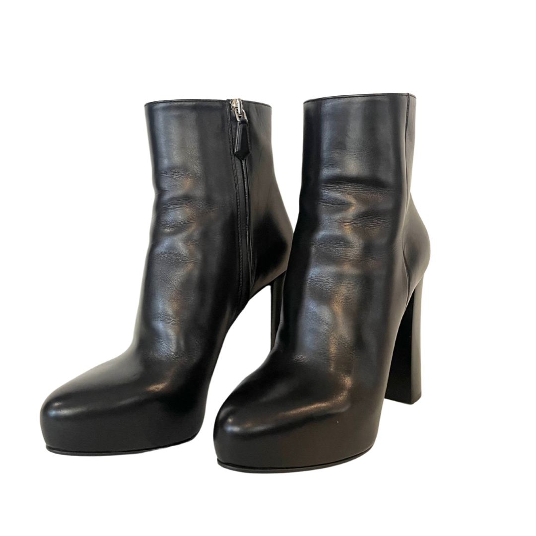 Scarpa stivaletto nero con gambale basso sopra alla caviglia in pelle liscia e leggermente a punta. Con logo oro sulla suola. Altezza del tacco: 11 cm con plateaux interno di 3 cm