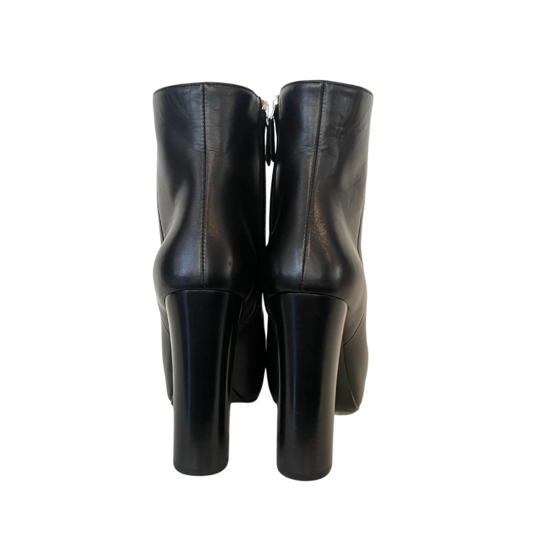 Scarpa stivaletto nero con gambale basso sopra alla caviglia in pelle liscia e leggermente a punta. Con logo oro sulla suola. Altezza del tacco: 11 cm con plateaux interno di 3 cm