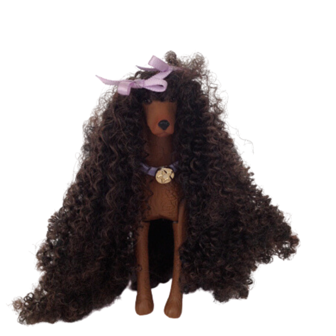 Si dice che il cane assomigli al proprio padrone ed è sicuramente il caso di questa Barbie che ha la chioma identica al pelo del suo animaletto!  Christie Barbie brilla con un abito sottoveste bordato in pizzo viola, con un cardigan coordinato rifinito in pelliccia sintetica viola e sabot viola. Sfoggia splendidi capelli ricci stretti accentati con fiocchi viola per abbinarli al suo vestito. 