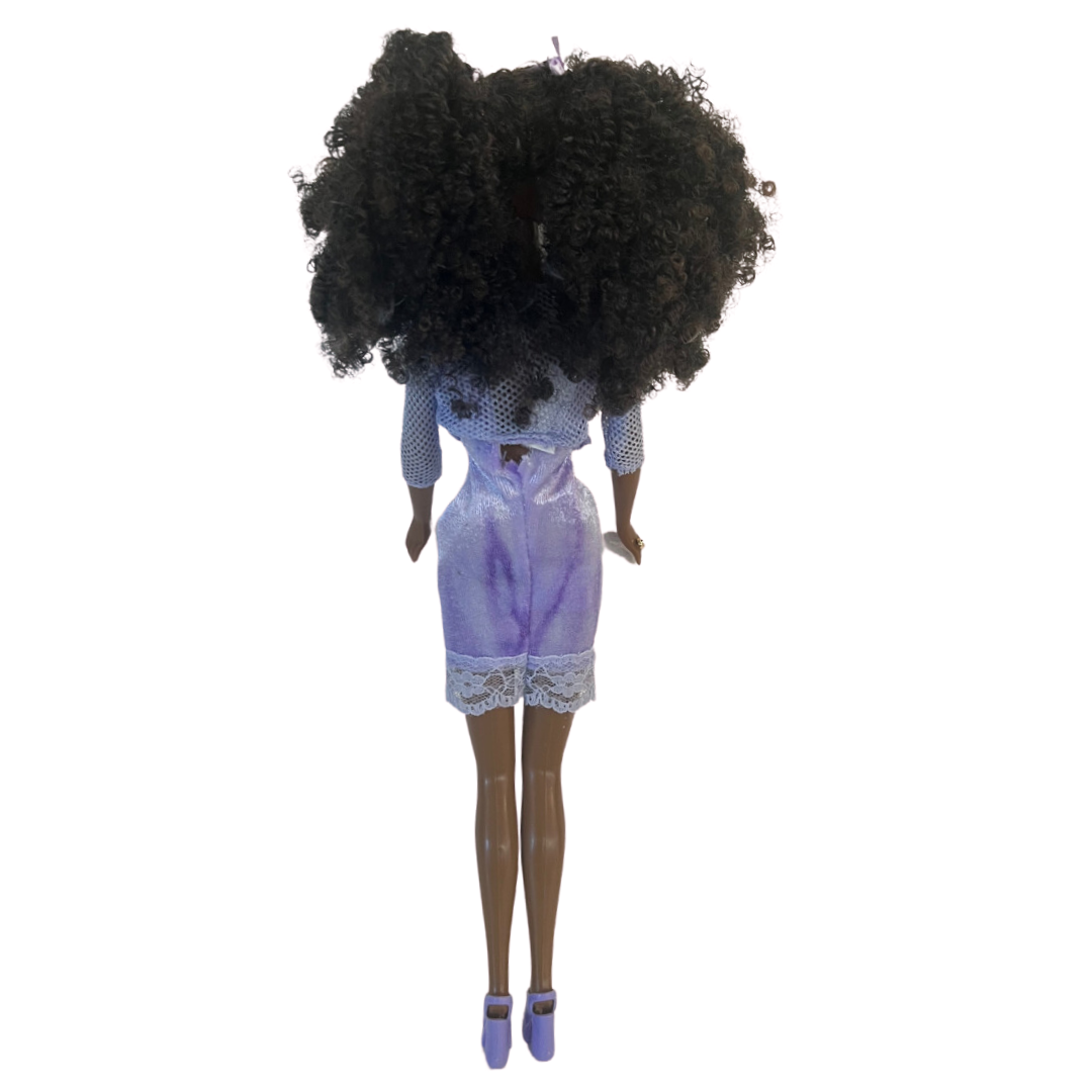 Si dice che il cane assomigli al proprio padrone ed è sicuramente il caso di questa Barbie che ha la chioma identica al pelo del suo animaletto!  Christie Barbie brilla con un abito sottoveste bordato in pizzo viola, con un cardigan coordinato rifinito in pelliccia sintetica viola e sabot viola. Sfoggia splendidi capelli ricci stretti accentati con fiocchi viola per abbinarli al suo vestito. 