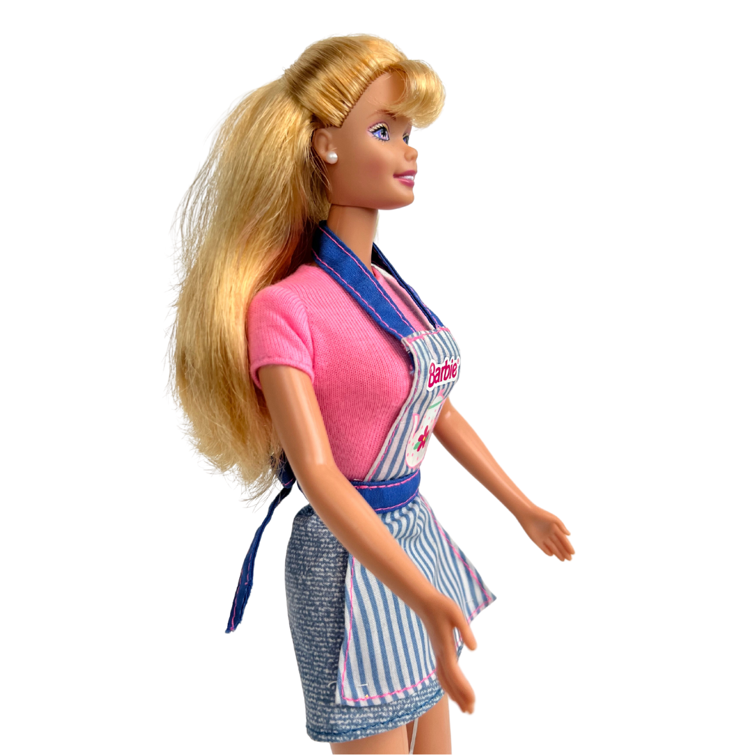Barbie Dolce Snack è una produzione Mattel del 1998.  Questa versione di Barbie dai lunghi capelli biondi, indossa t-shirt rosa, una gonna corta in jeans e un grembiule da cucina rigato blu e bianco con rifiniture rosa, una cintura e bretelle in jeans, delle scarpe bianche.