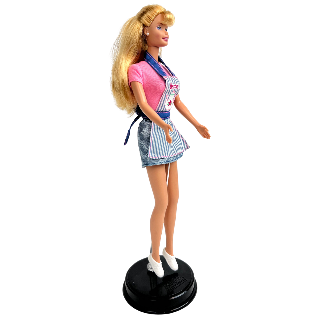 Barbie Dolce Snack è una produzione Mattel del 1998.  Questa versione di Barbie dai lunghi capelli biondi, indossa t-shirt rosa, una gonna corta in jeans e un grembiule da cucina rigato blu e bianco con rifiniture rosa, una cintura e bretelle in jeans, delle scarpe bianche.