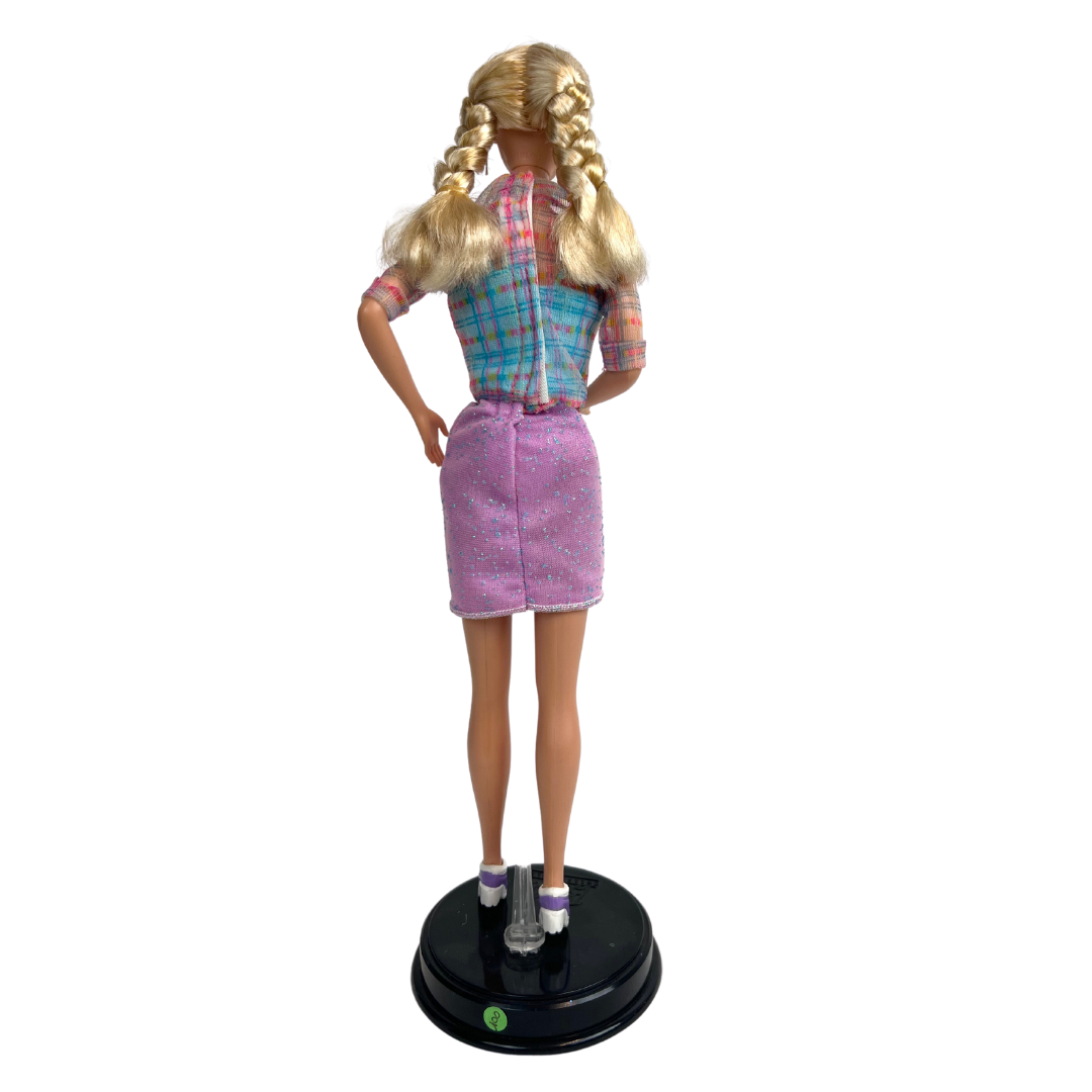    La bambola Barbie dai capelli biondi e occhi azzurri indossa una gonna viola scintillante, un top blu con strisce trasparenti sopra, un paio di scarpe viola e bianche.     manca passeggino e bambola piccola 