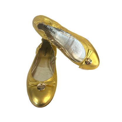 Ballerine in pelle oro metallizzata, punta stondata e elastico sul tallone, piccolo fiocco con medaglietta tonda con logo