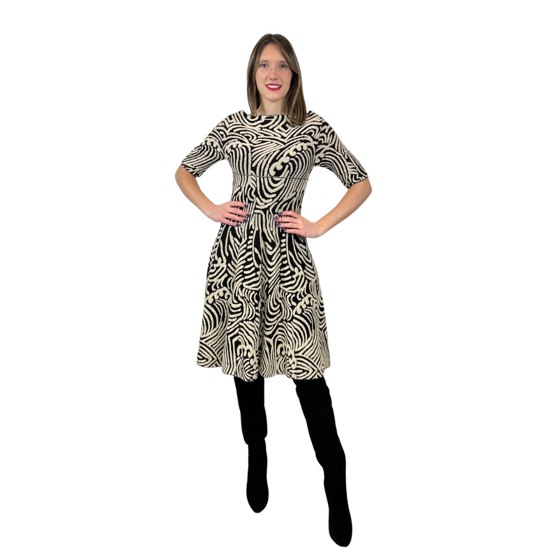 Abito in maglia di lana con fondo nero e con disegni irregolari sui toni del beige chiaro. Collo a barchetta e gonna a ruota, manica a 3/4.  Tg. L