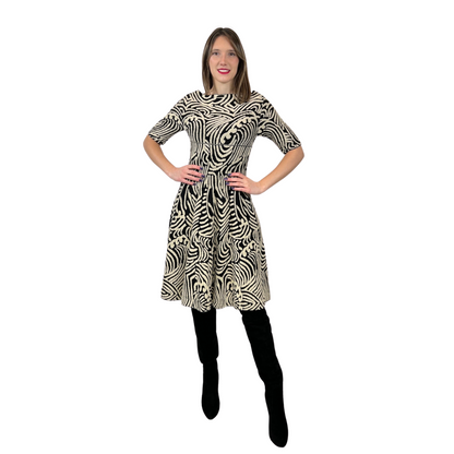 Abito in maglia di lana con fondo nero e con disegni irregolari sui toni del beige chiaro. Collo a barchetta e gonna a ruota, manica a 3/4.  Tg. L