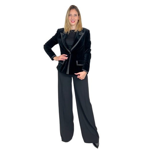 Giacca blazer in velluto rasato nero con una bordatura in raso.  La chiusura è ad un bottone, dotata di due patelle applicate.